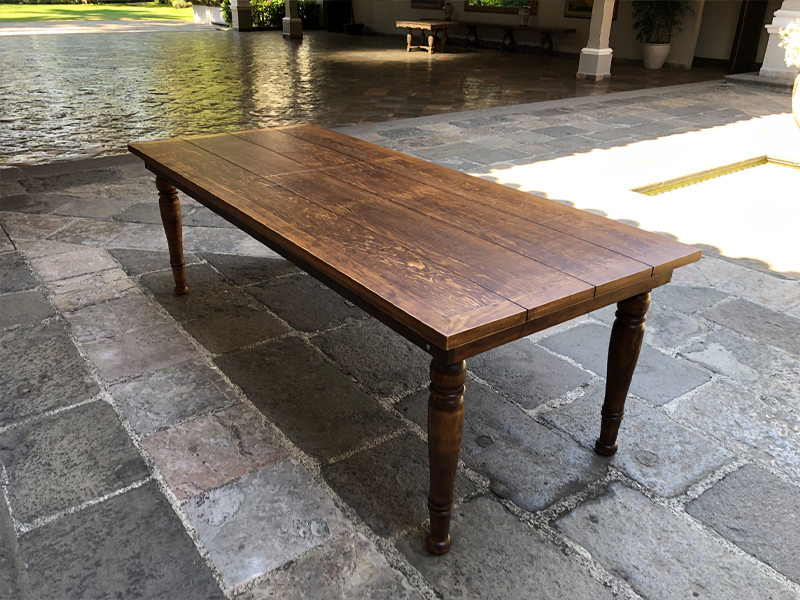 Tablón de madera con patas redondas, color rústico royal, ubicado en un espacio pavimentado al aire libre.
